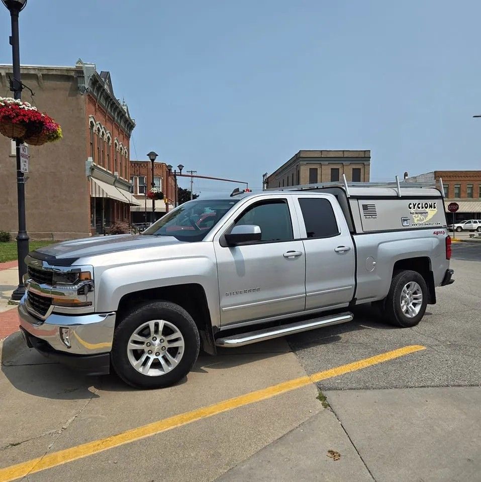 A silver truck is parked on the side of the road in front of a building.