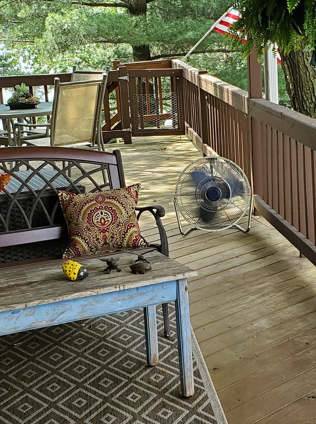 A wooden deck with a couch, chairs, a table, and a fan.