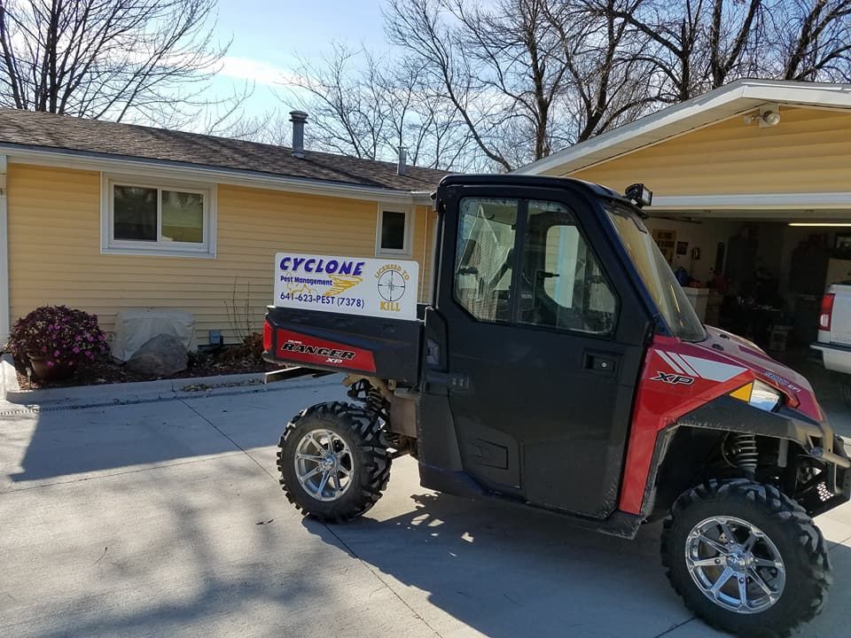 A red atv is parked in front of a yellow house.