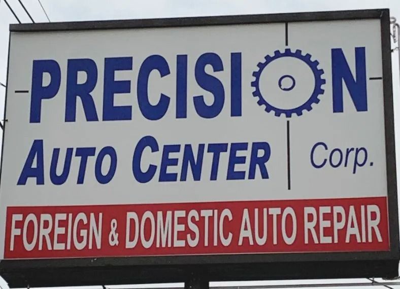 Sign for Precision Auto Center: blue text on white background, red banner below. States 