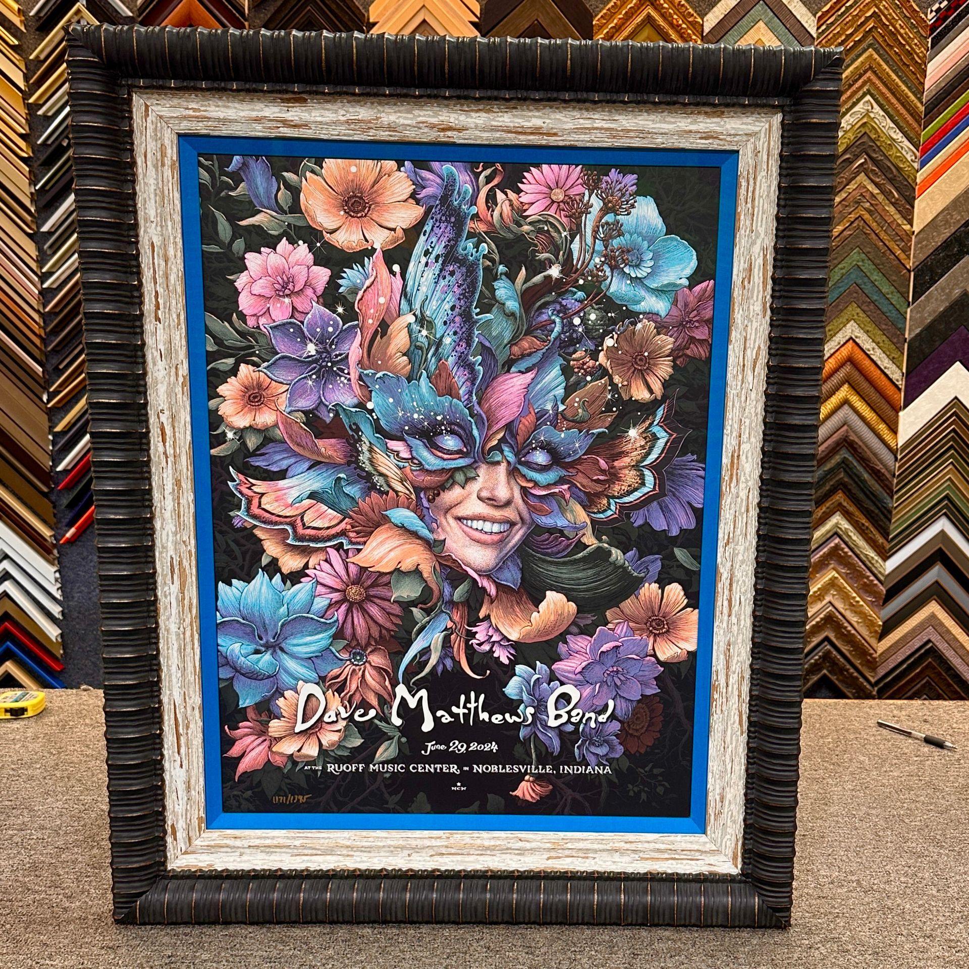 Framed artwork of a smiling person with a mask surrounded by colorful flowers.