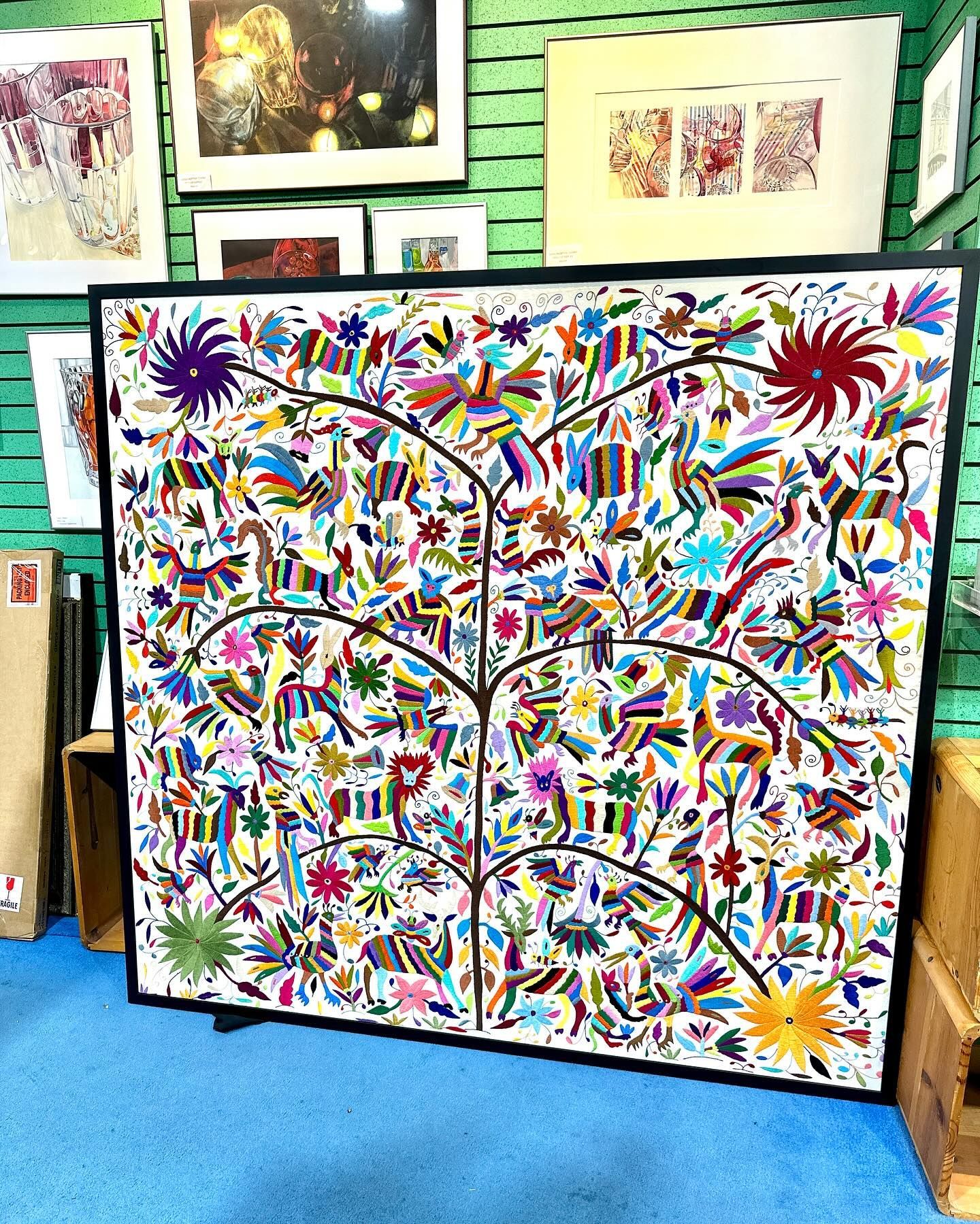 Colorful folk art tree painting in a black frame.  Animals and flowers on branches against a white background.