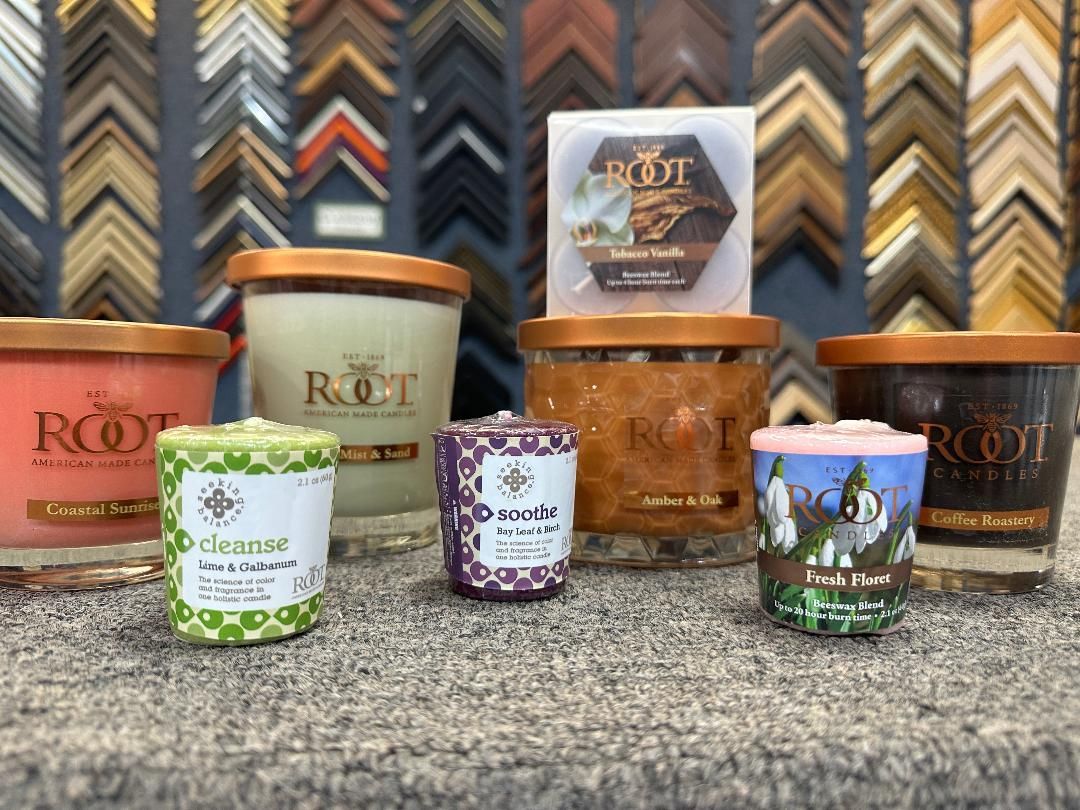 Candles of various sizes and scents on display in front of frame samples.