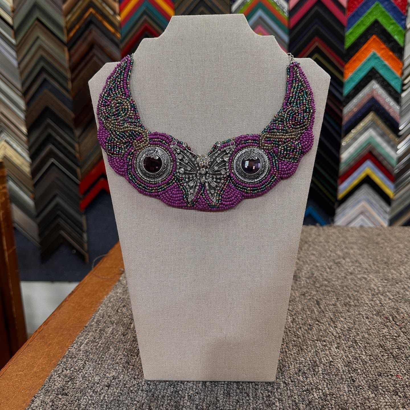 Beaded purple and gray necklace on a display stand, with gemstone accents.