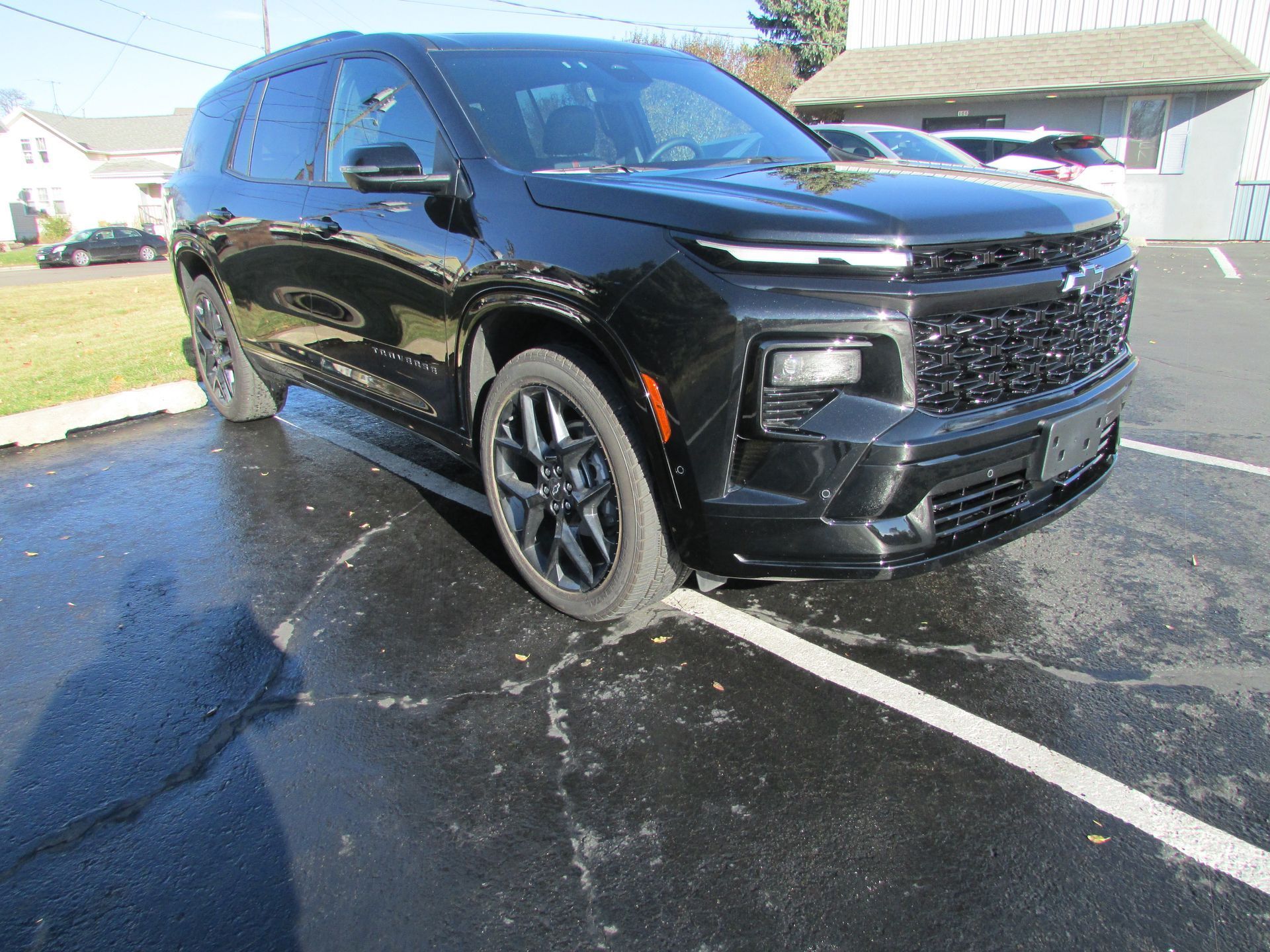 Black Chevrolet SUV parked on wet pavement in a parking lot.