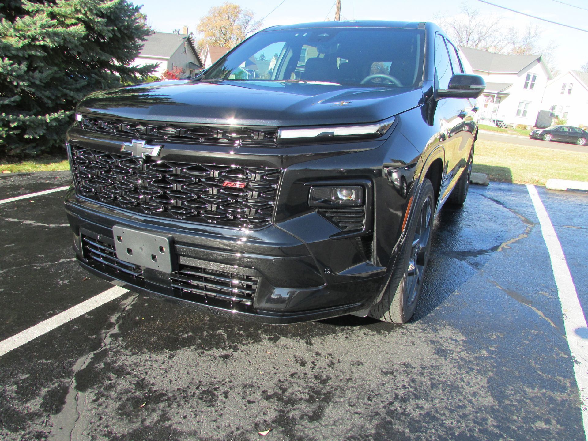 Black Chevrolet SUV parked on wet pavement.