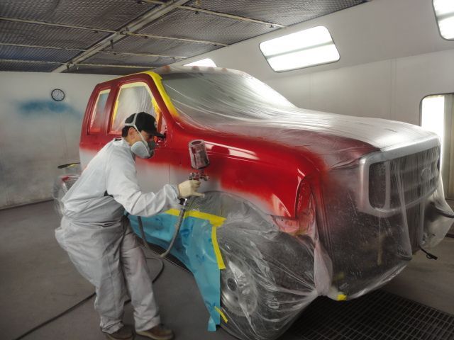 red pick-up truck with crew during paint job