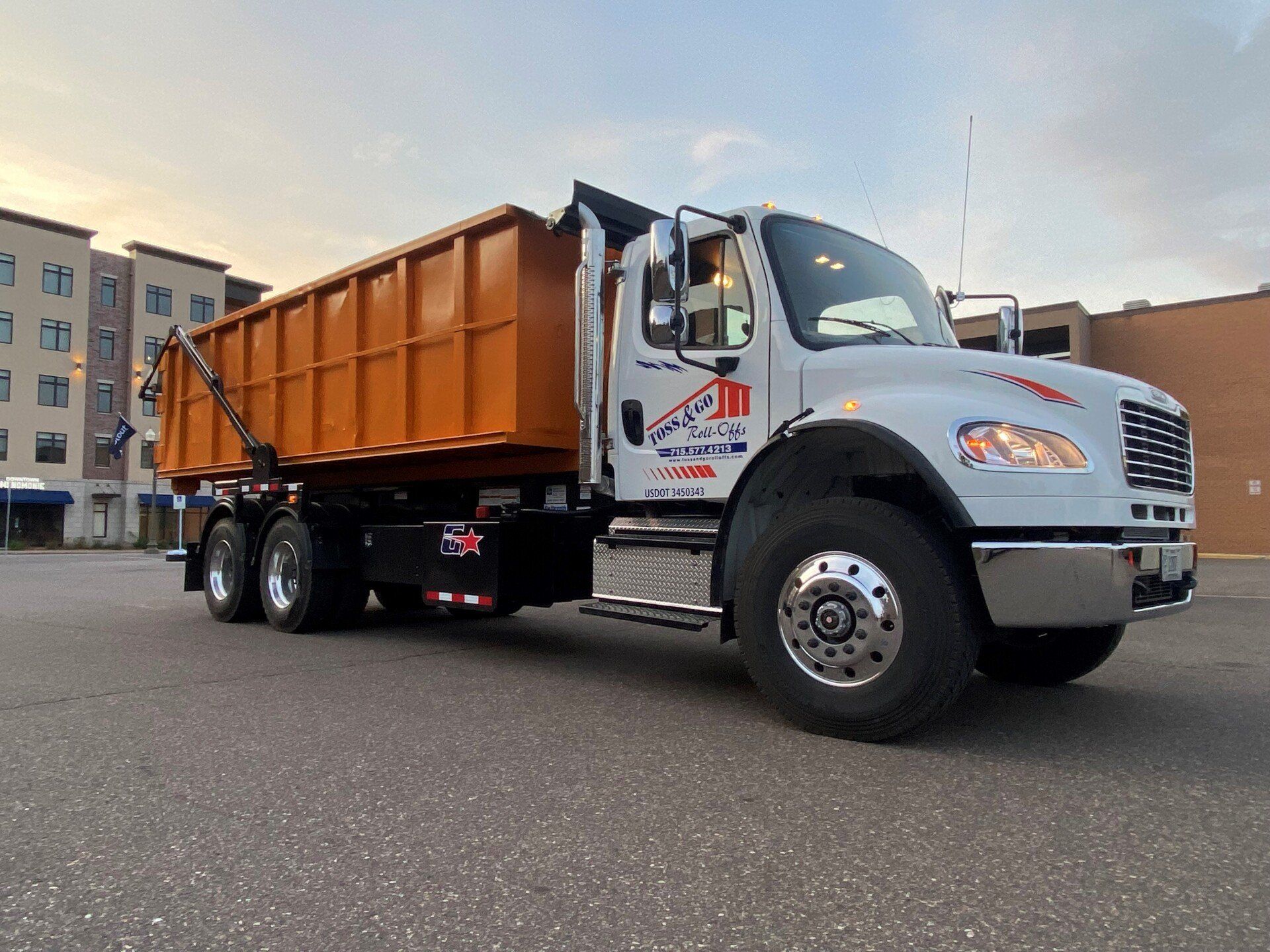 Truck transporting a roll off dumpster