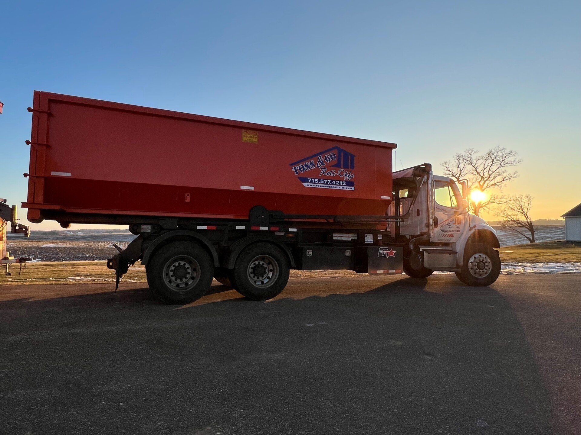 Truck transporting a roll off dumpster