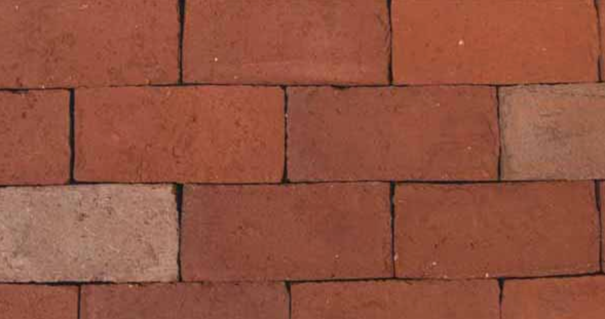 Red brick wall with a few lighter tan bricks mixed in, arranged in a horizontal pattern