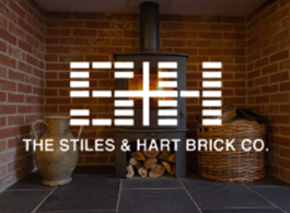 Brick fireplace with stacked logs and wicker baskets under The Stiles & Hart Brick Co. sign