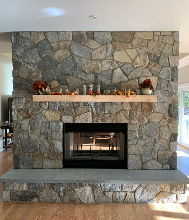 Stone fireplace with a white mantel and autumn decorations in a bright room
