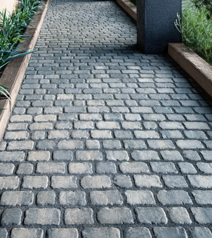 Stone-paved walkway bordered by wooden planters and greenery