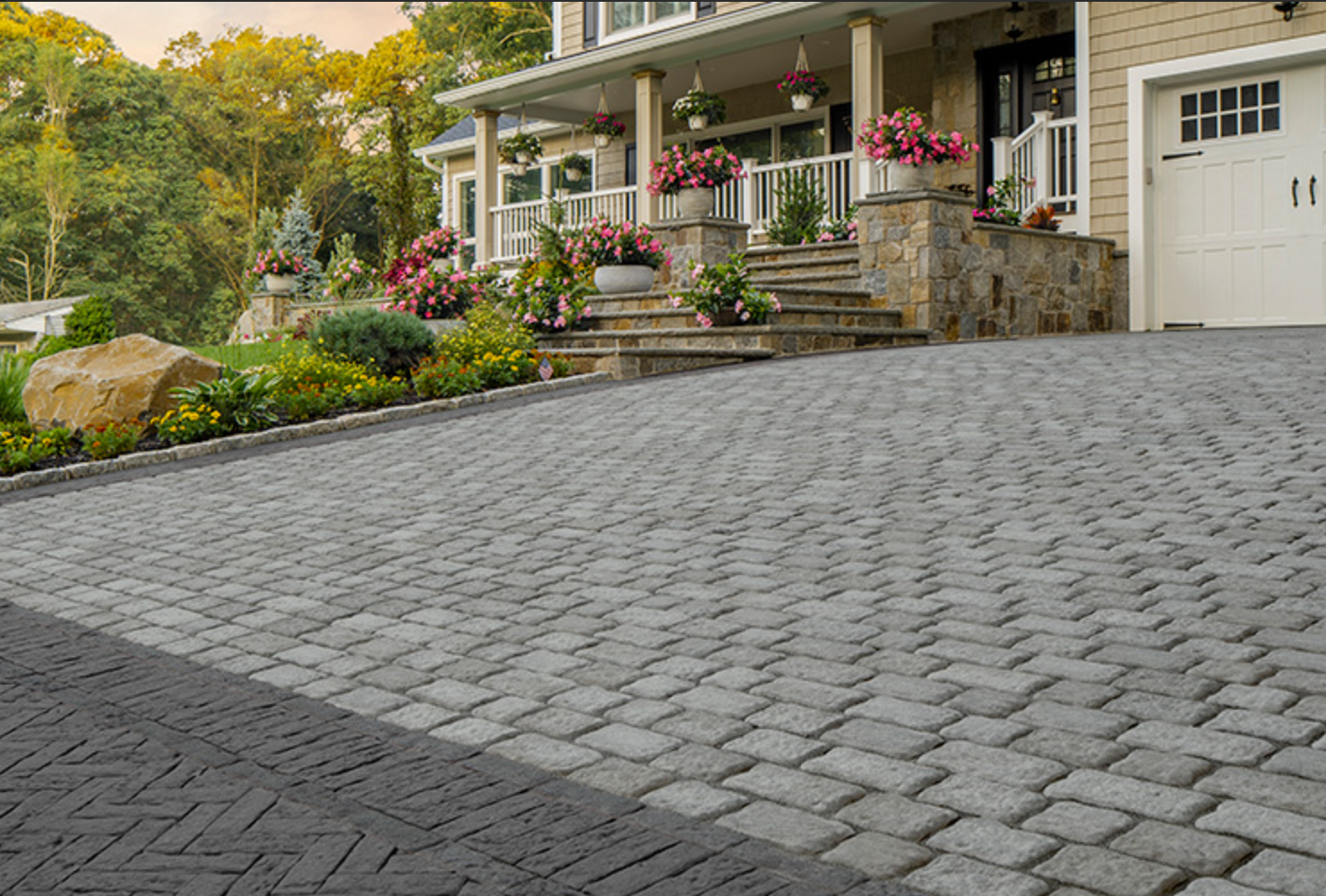 Stone driveway leading to a house with porch, flowers, and landscaped garden