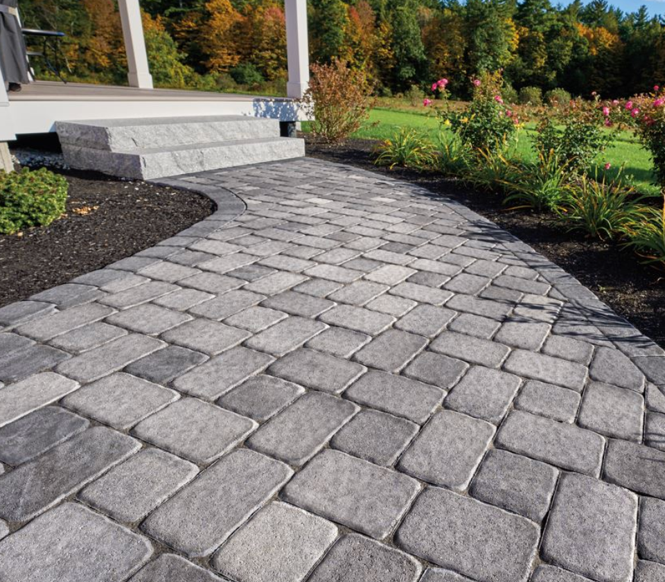 Curved stone paver walkway beside steps and landscaped garden with autumn foliage
