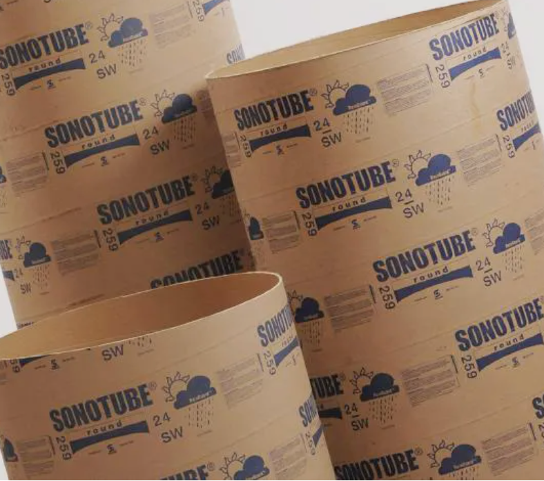 Stacks of brown Sonotube cardboard concrete form tubes with blue branding in a warehouse or storage area