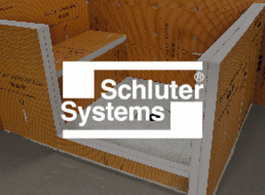 Schluter Systems logo on orange construction boards in a tiled corner display