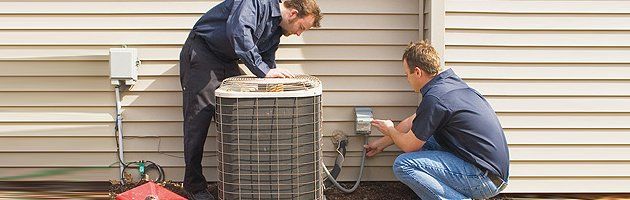 Two repairmen working on a AC unit