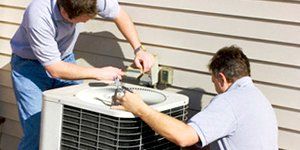 Two men working on AC unit