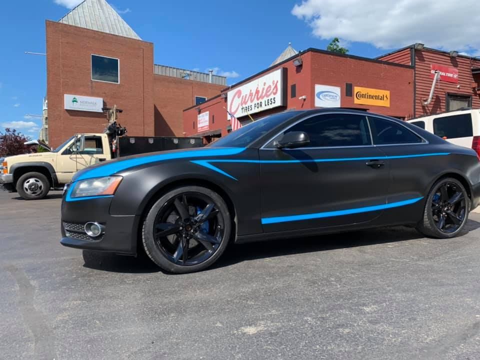 a black car with blue stripes is parked in front of a building that says cherry 's
