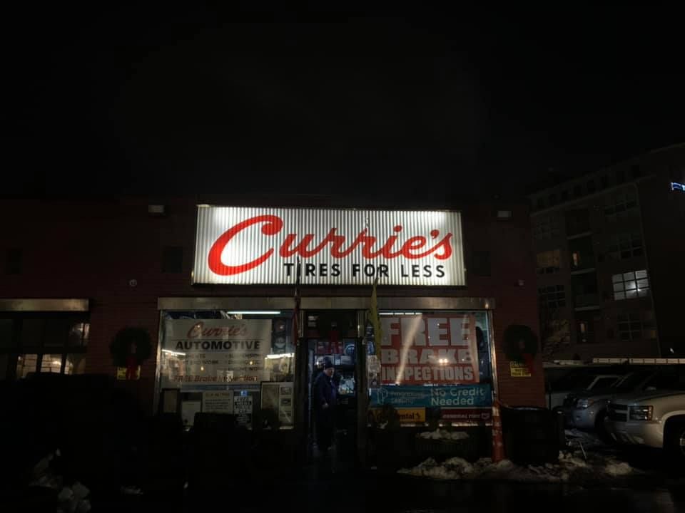 a sign for carrie 's tires for less is lit up at night