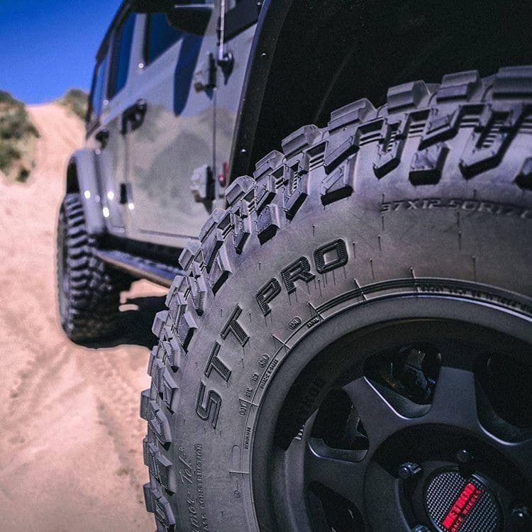 a close up of a tire on a jeep on a dirt road