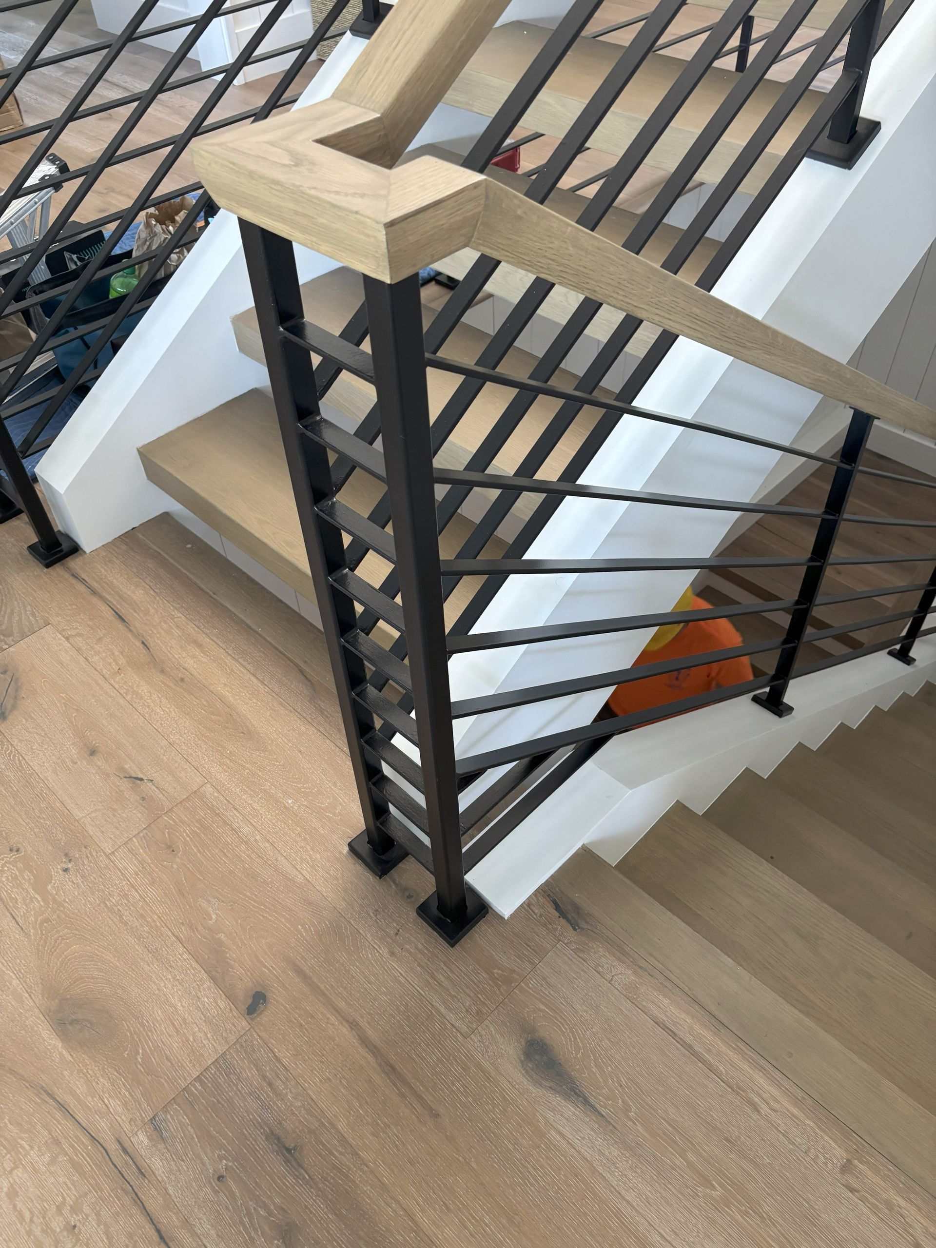 Wooden staircase with black metal railing and wooden handrail.