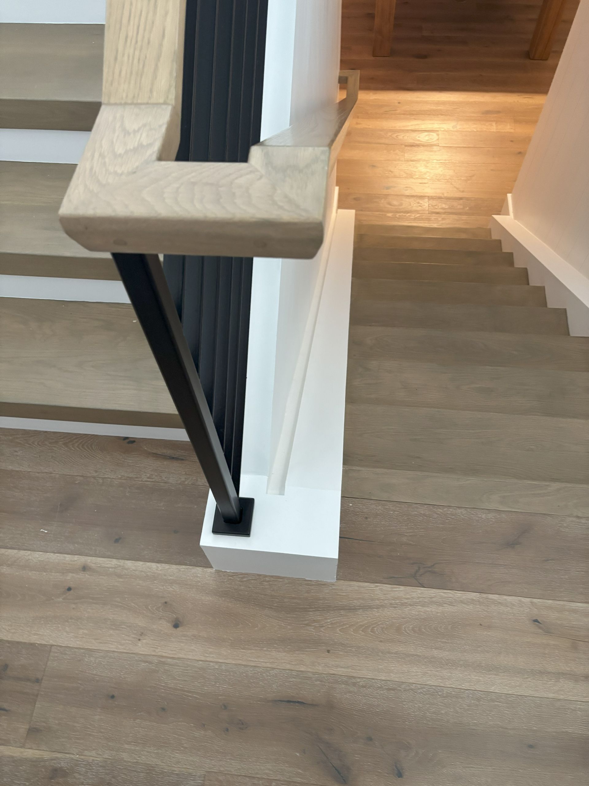 Wooden staircase with black metal railing and white trim.