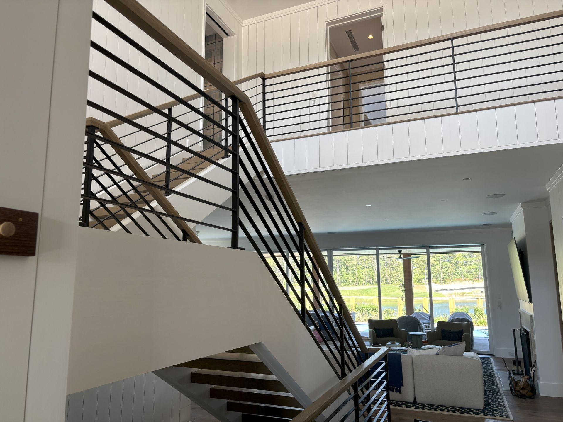 Modern home interior with staircase, black railings, and light wood accents.