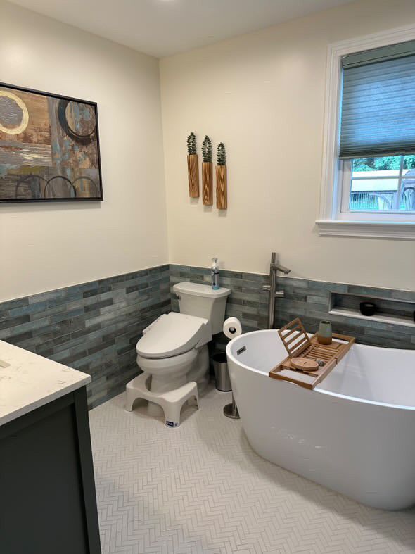 A bathroom with a tub , toilet , sink and window.