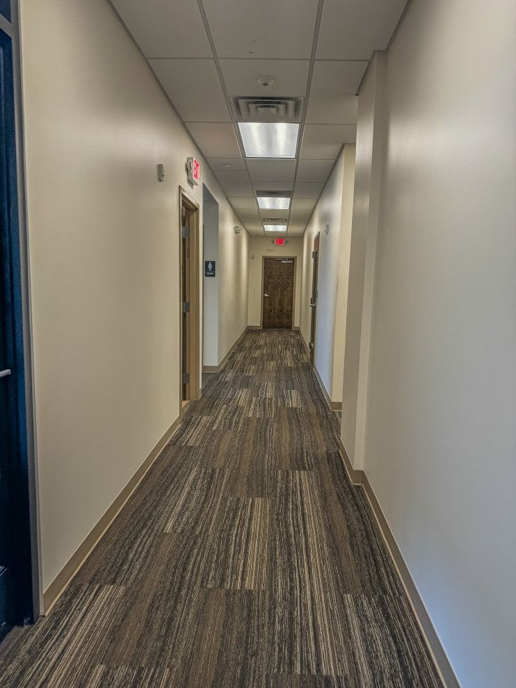 A long hallway with a carpeted floor and white walls.