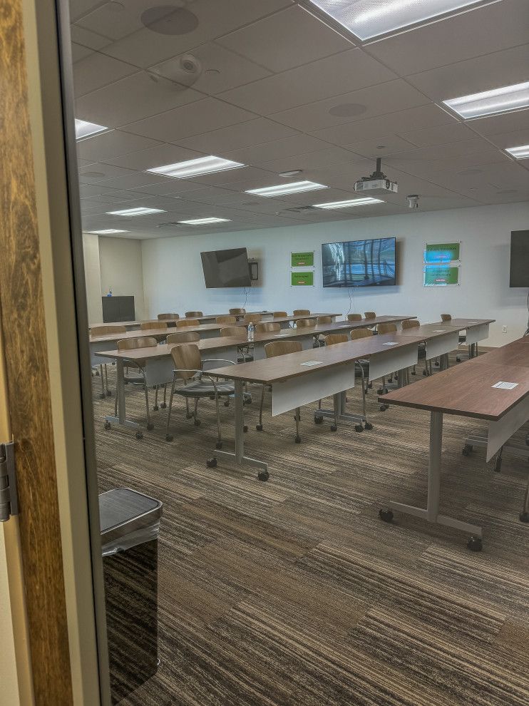 A classroom with tables and chairs and a projector on the wall.