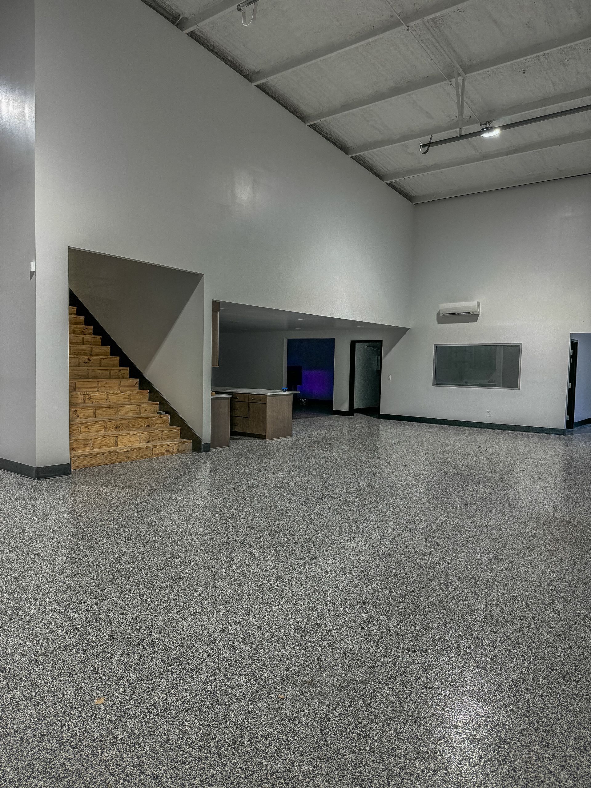 A large empty room with a staircase leading up to the second floor.