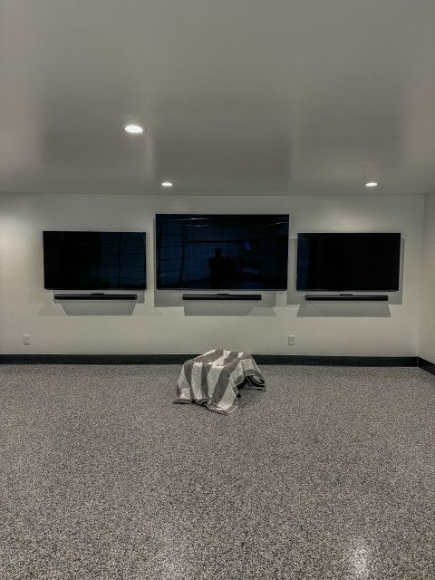 A room with three televisions on the wall and a blanket on the floor.