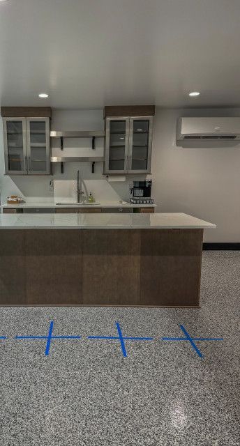A kitchen with a large island and a blue tape on the floor.