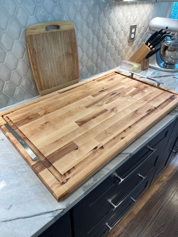 A large wooden cutting board is sitting on top of a kitchen counter.