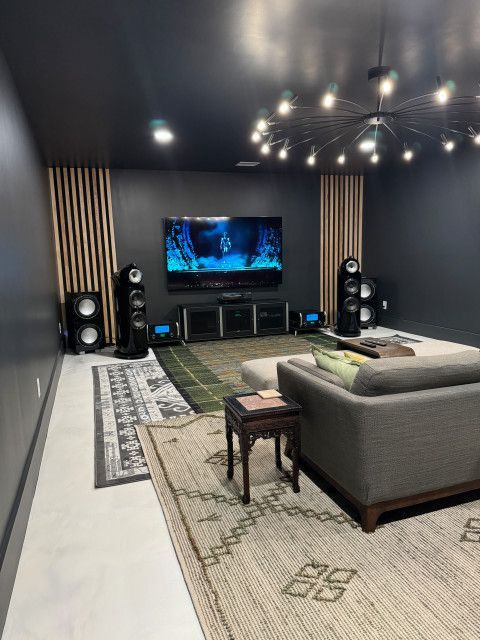 A living room with a couch , television , speakers and a rug.