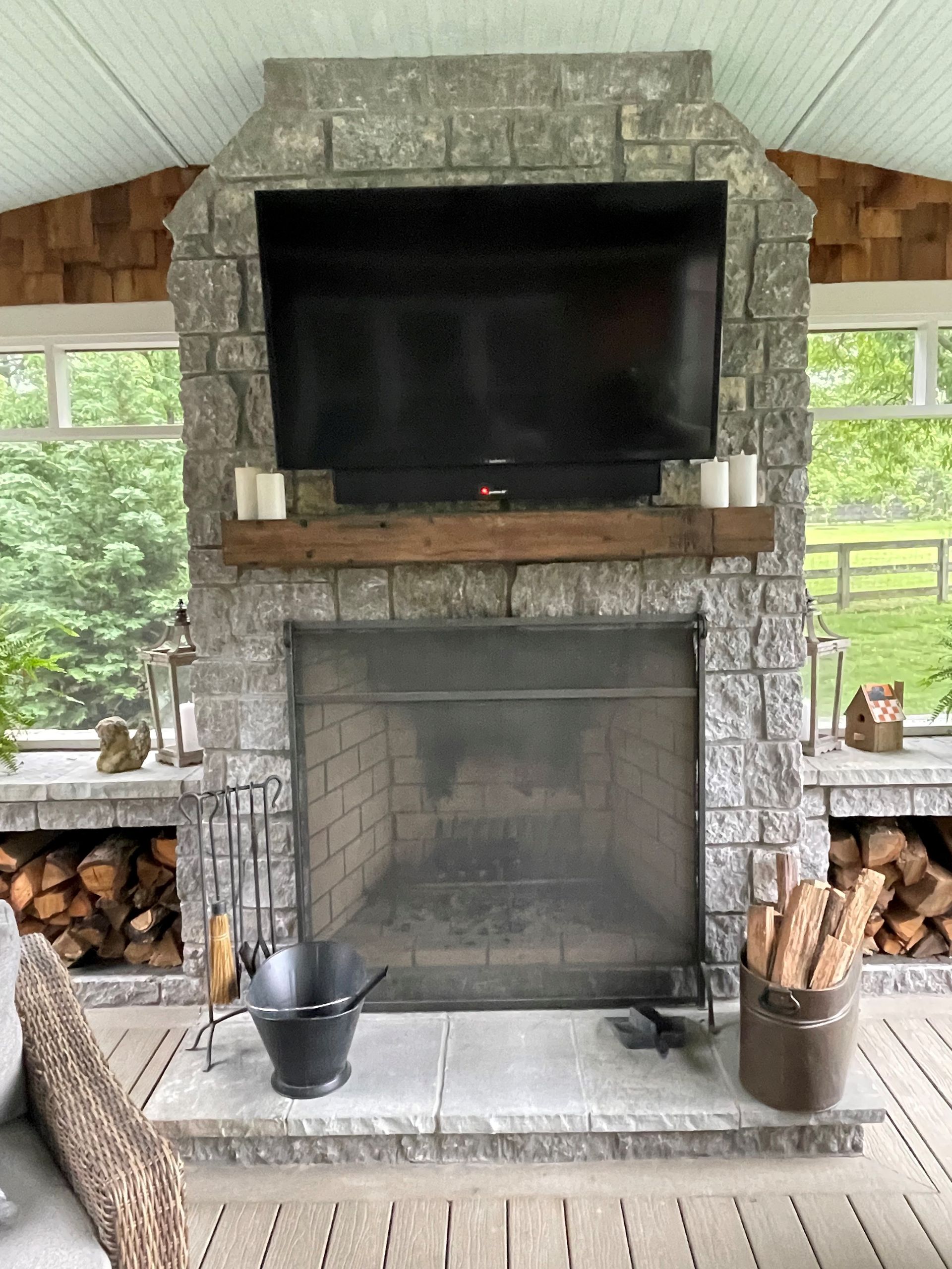 A large stone fireplace with a flat screen tv above it.