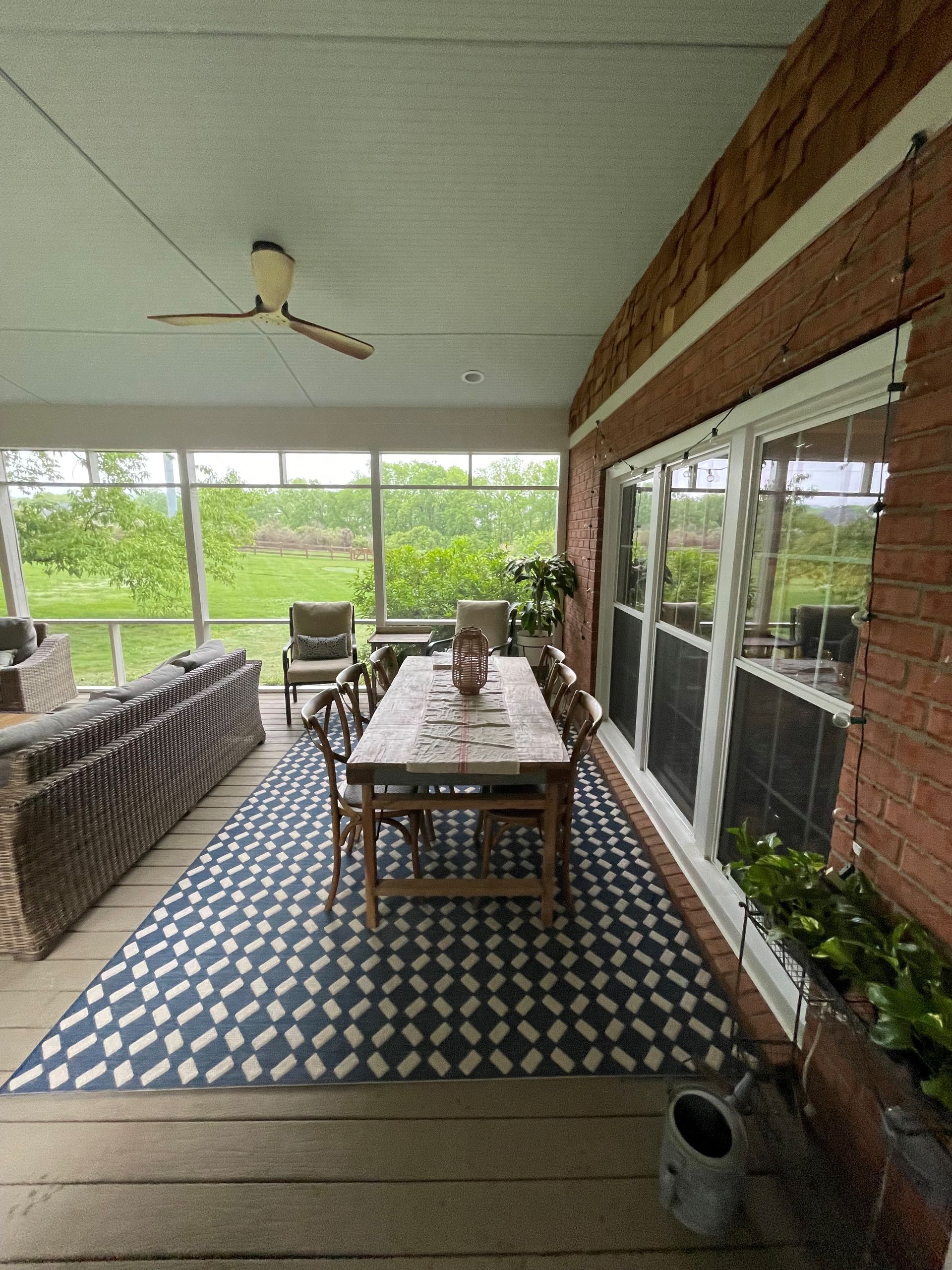 A screened in porch with a table and chairs and a rug.