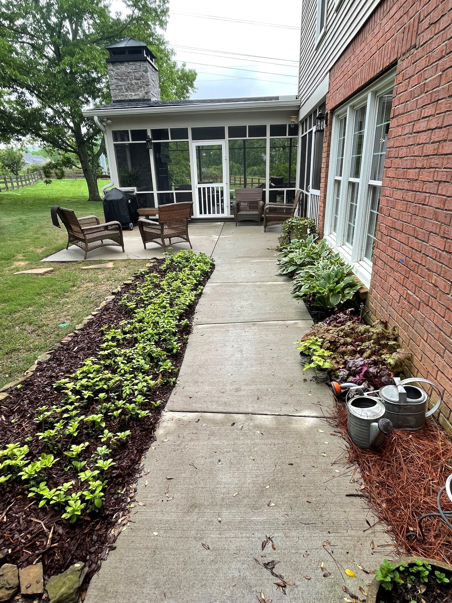 A brick house with a screened in porch and a walkway leading to it.