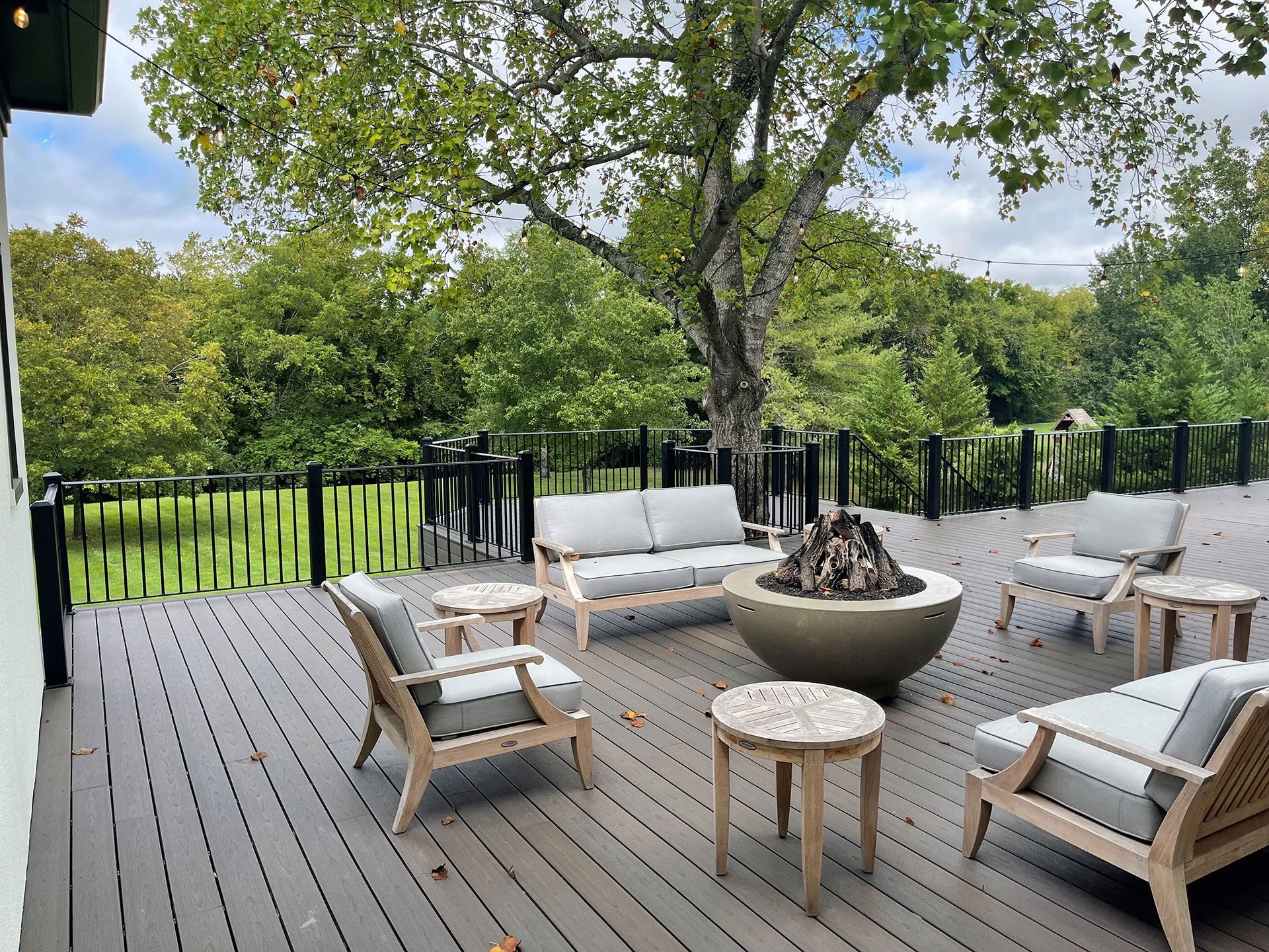There is a fire pit on the deck with chairs and a couch
