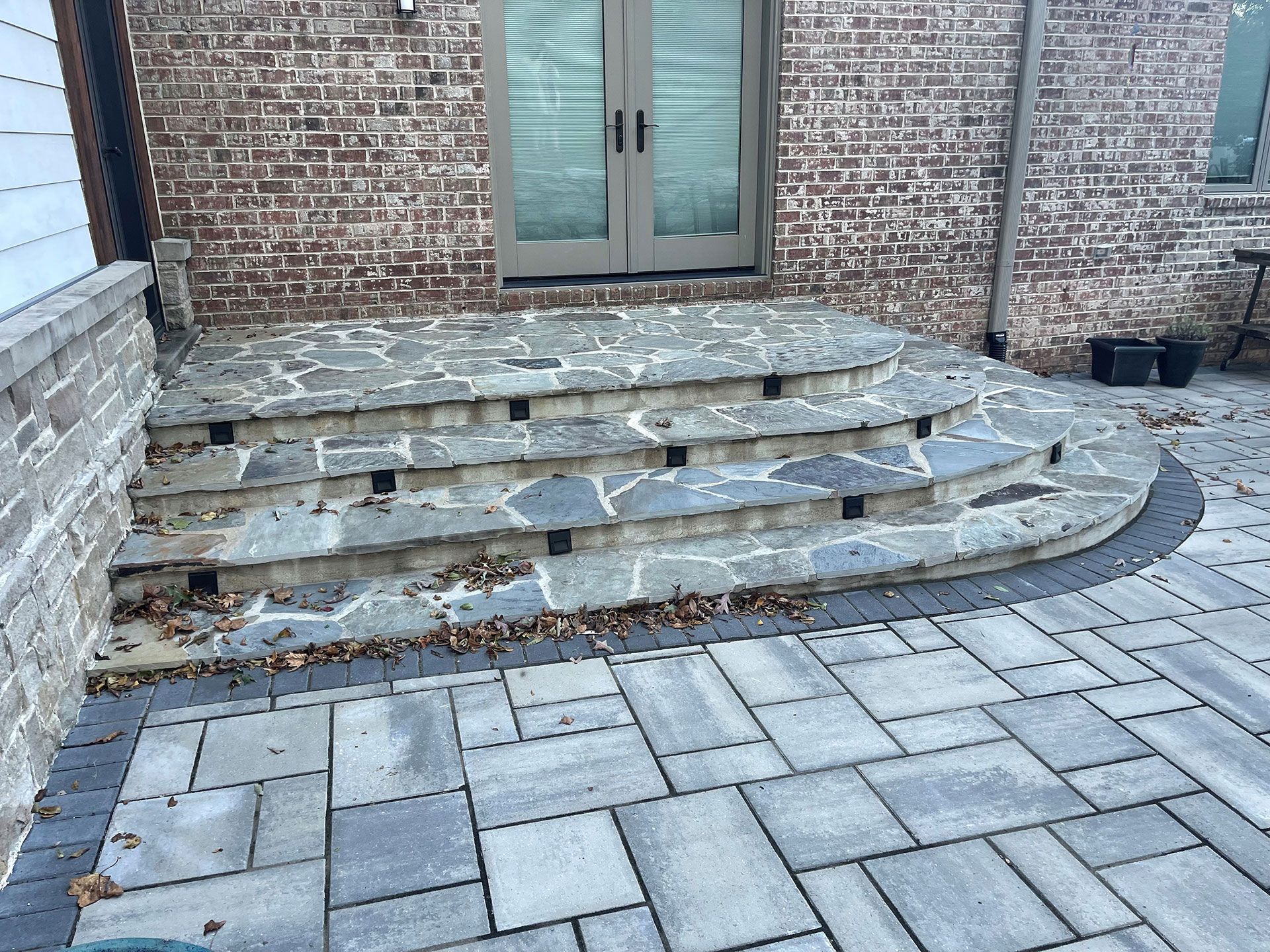 A stone patio with stairs leading up to a brick building
