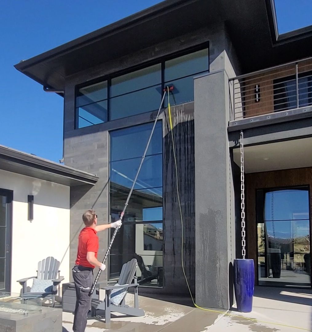 A man is cleaning a window with a long pole.
