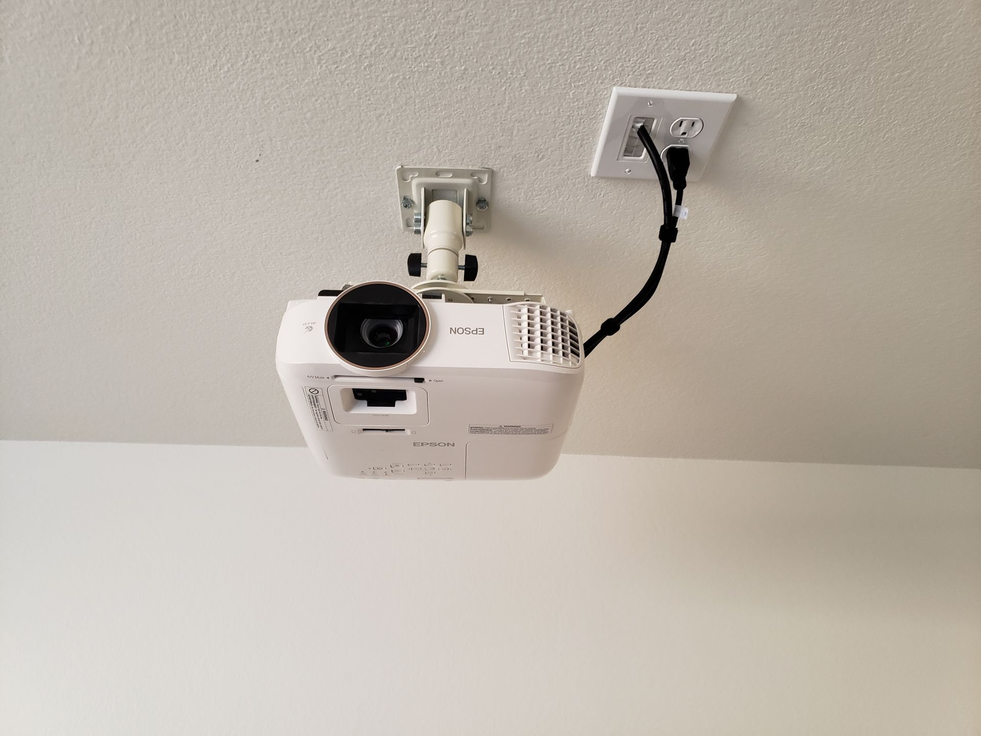 A projector is hanging from the ceiling in a room.