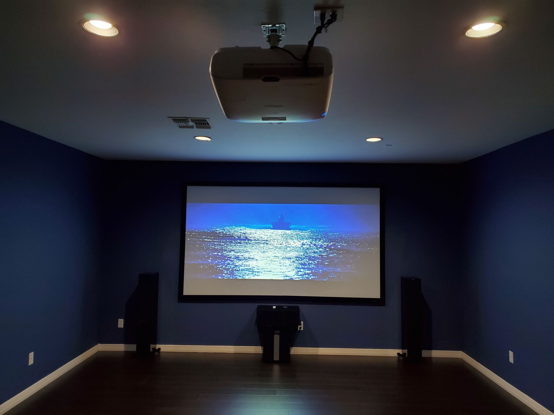 A projector is hanging from the ceiling in a dark room