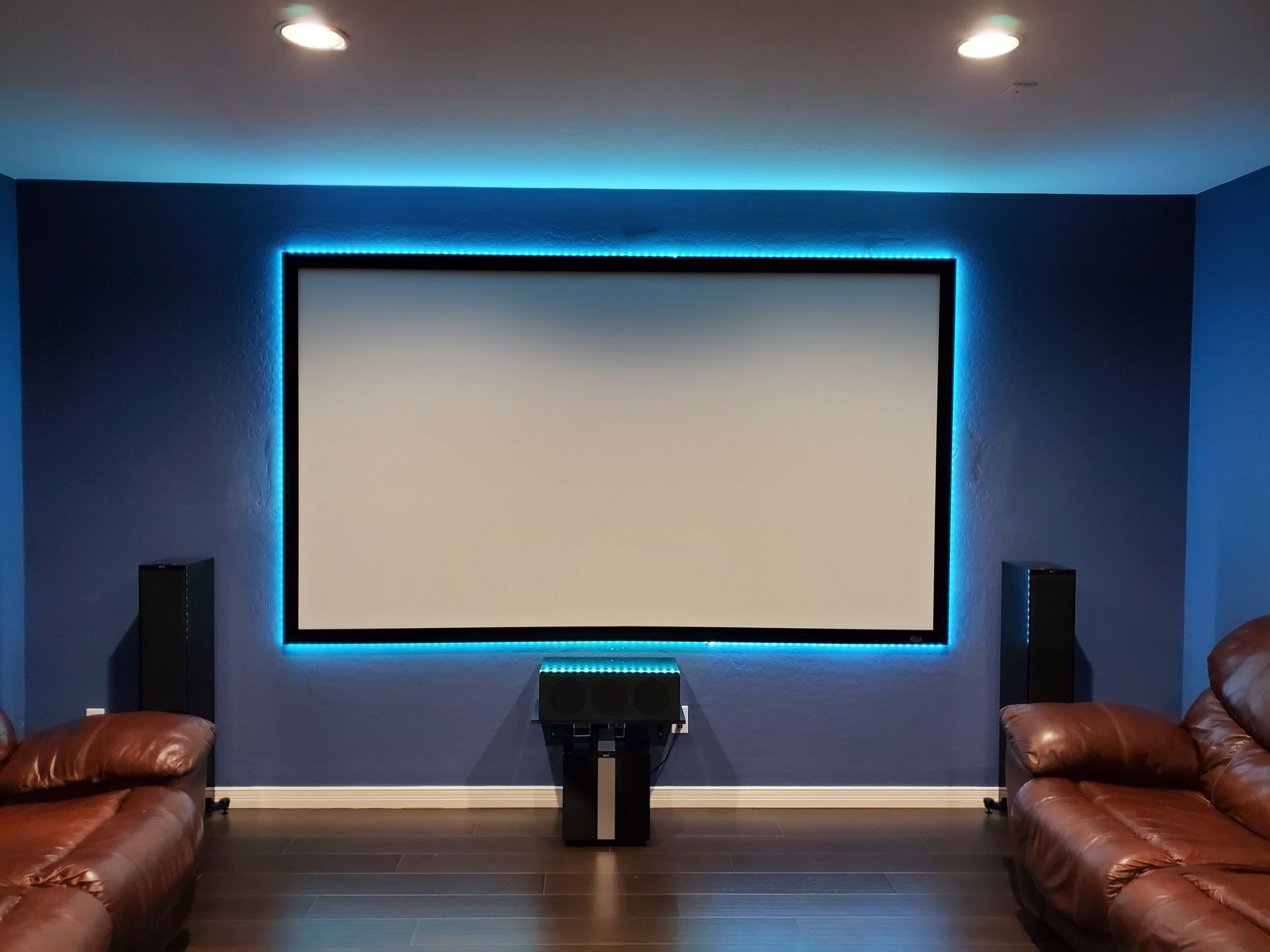 A home theater with a projector screen hanging on the wall.