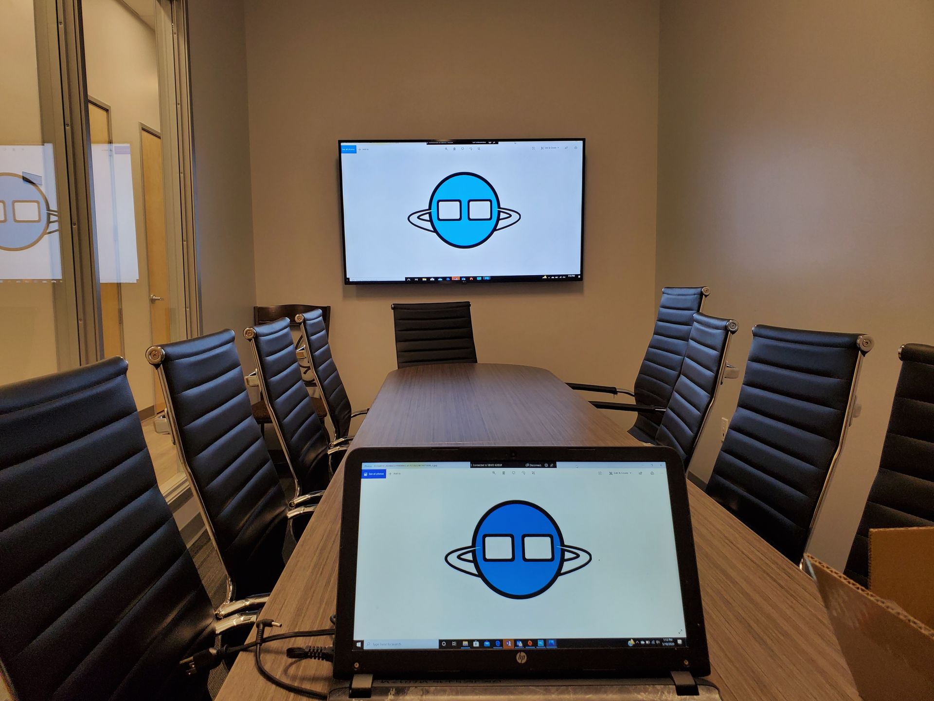 A conference room with a long table and chairs and a laptop on the table