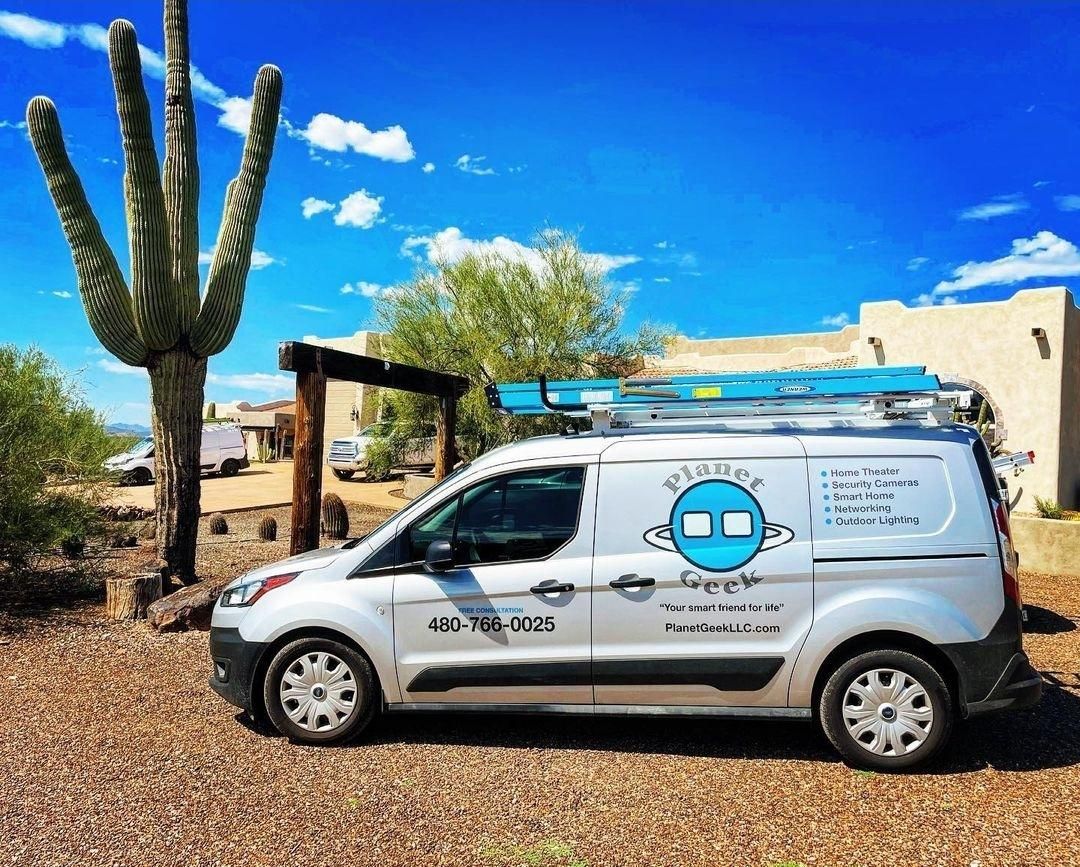 A white van is parked in front of a saguaro cactus.