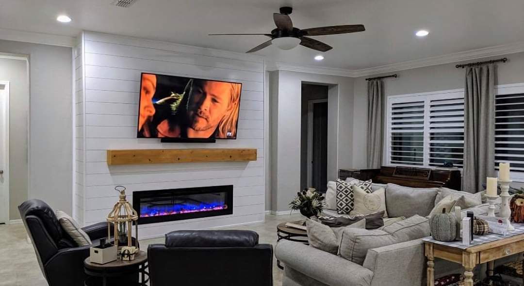A living room with a fireplace , couch , chair and television.