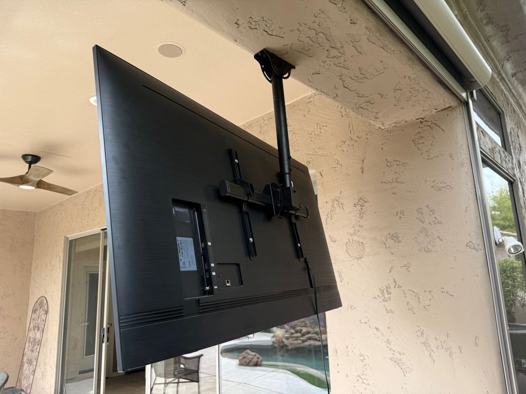 A flat screen tv is hanging from the ceiling in a room.